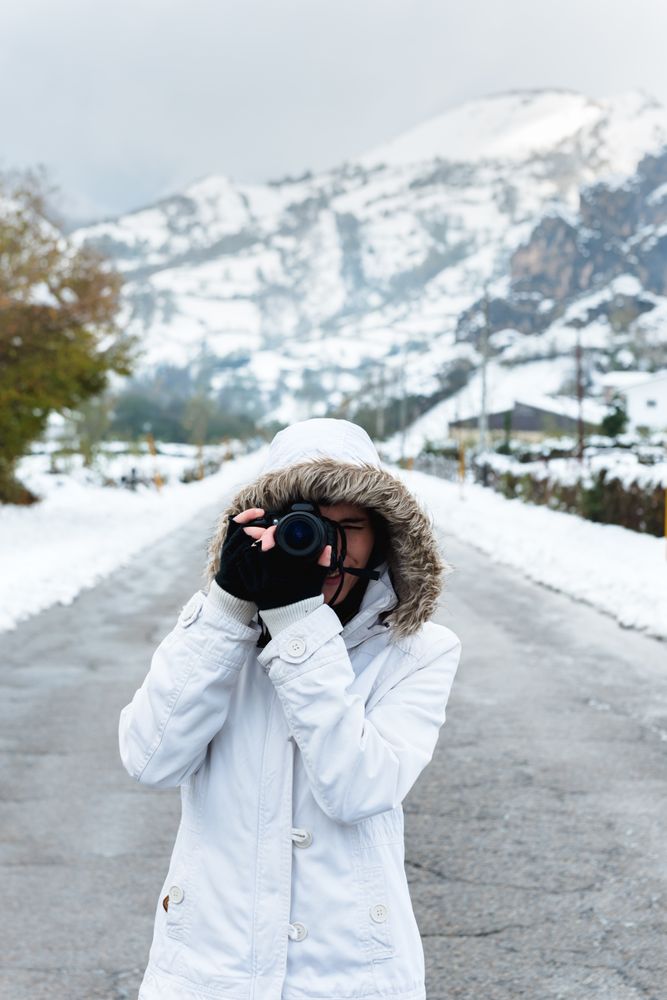 Content woman taking picture in snowy mountains