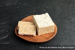 Block of fresh tempeh on wooden plate 5rRe25