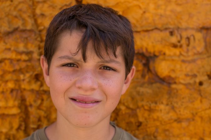 Young boy looking at camera with yellow background