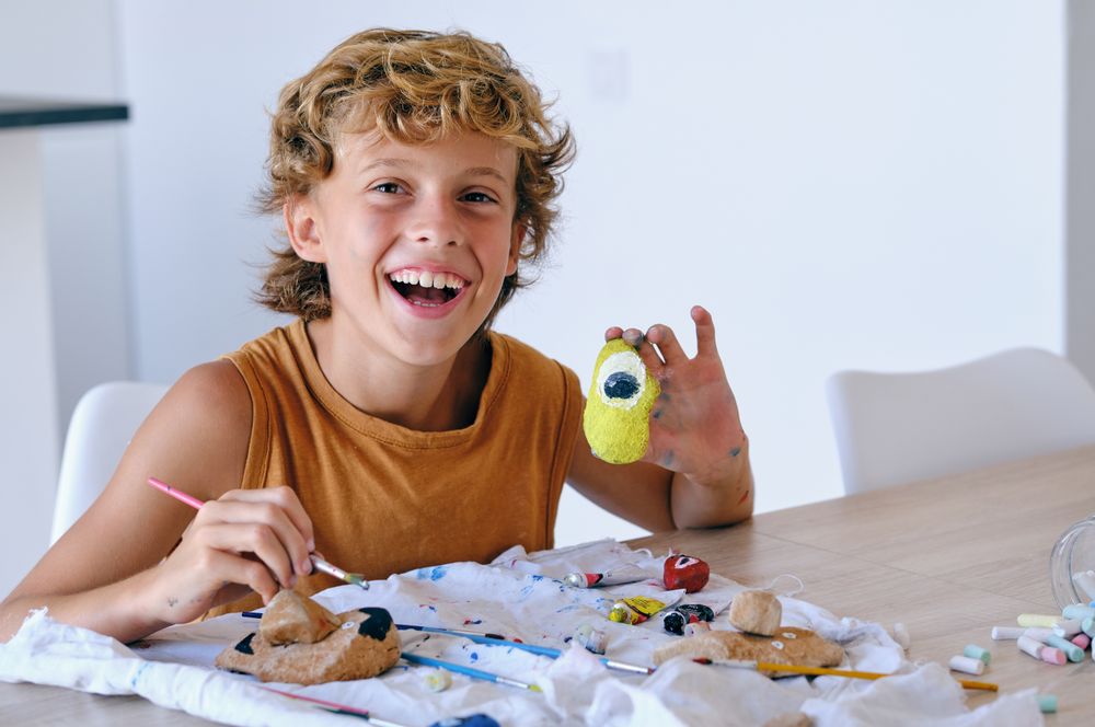 Happy boy painting stone at home