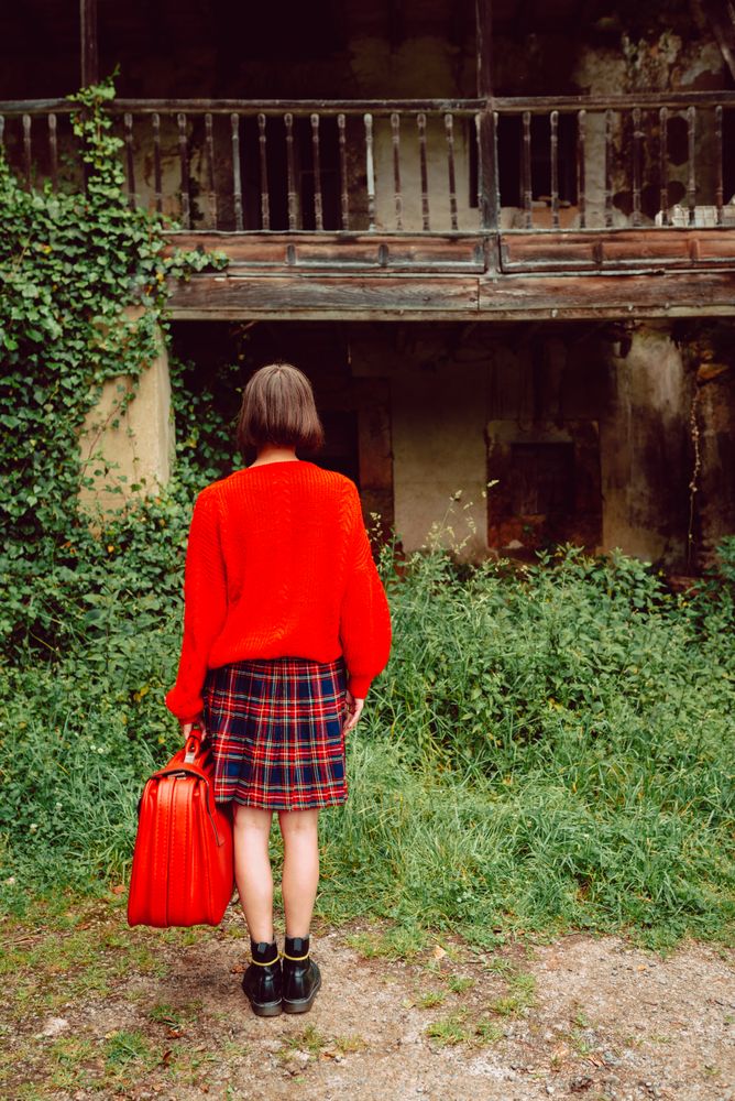 Woman in red with big red suitcase in forest