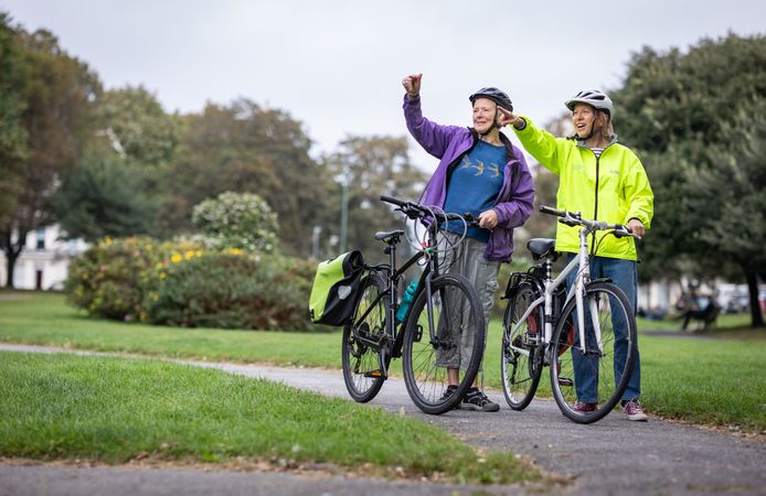 Two older people standing and pointing with bikes