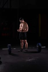 Man sportsman preparing for lifting barbell with plates