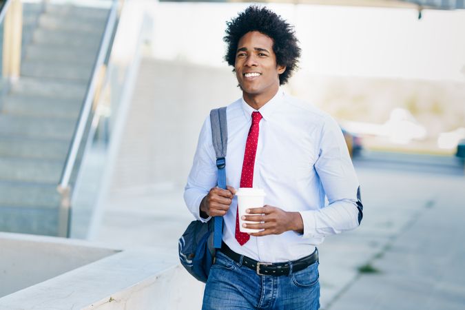 Smiling man with coffee walking down stairs