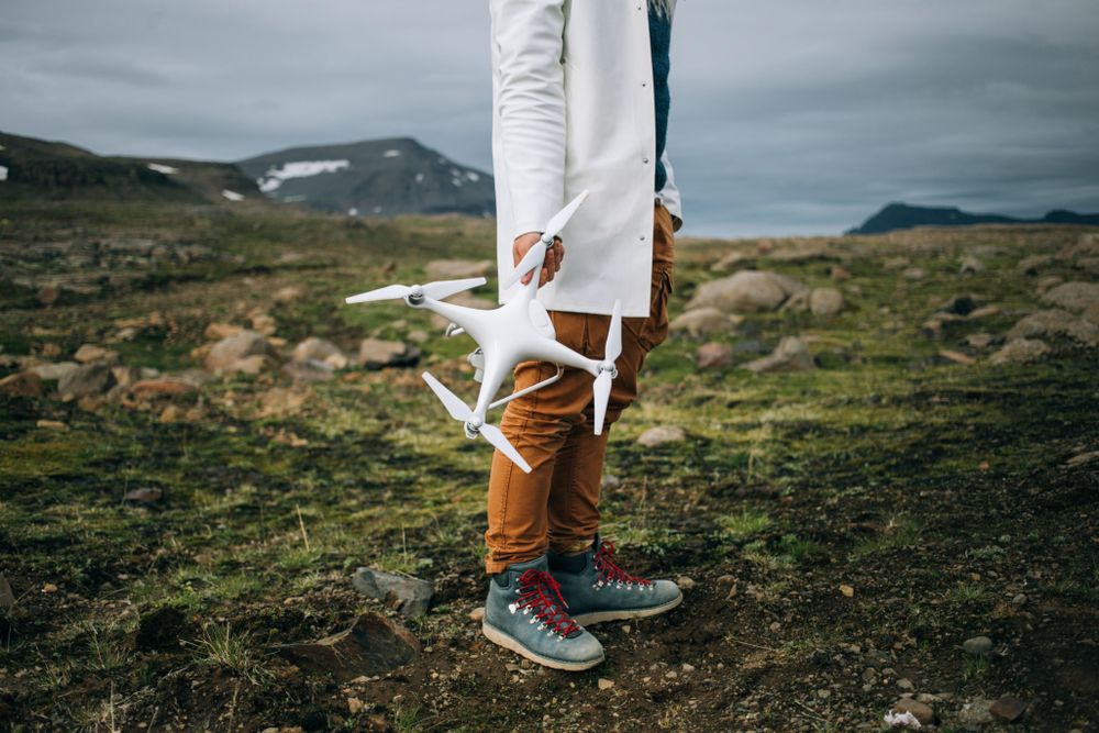 Man holding drone in rugged terrain