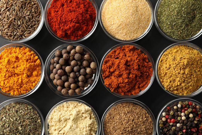 Close up of rows of bowls of spices on dark table