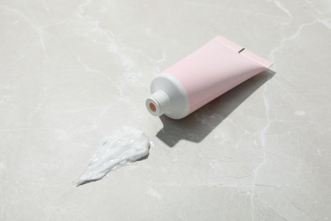 Blank pink tube of cream on light background