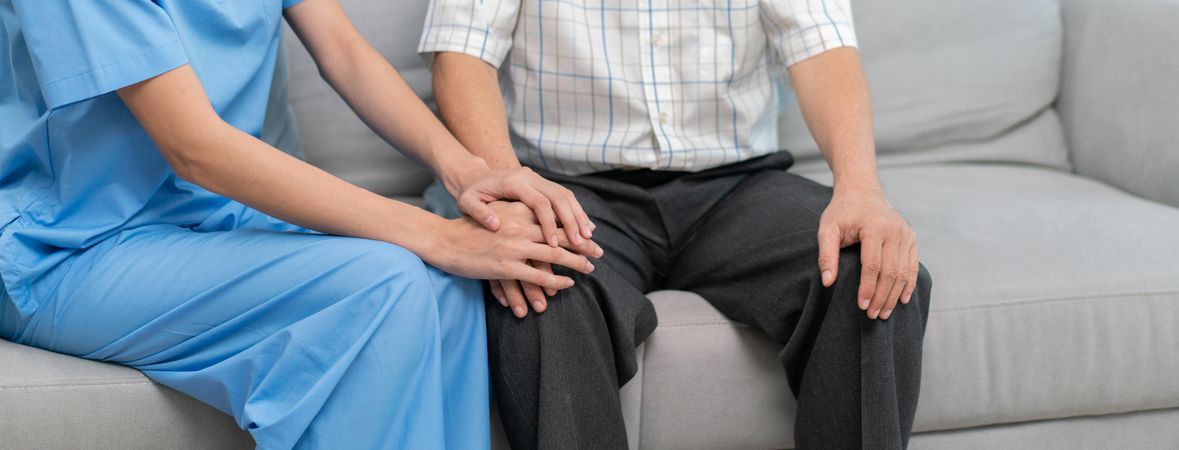 Medical staff supporting patient on grey couch