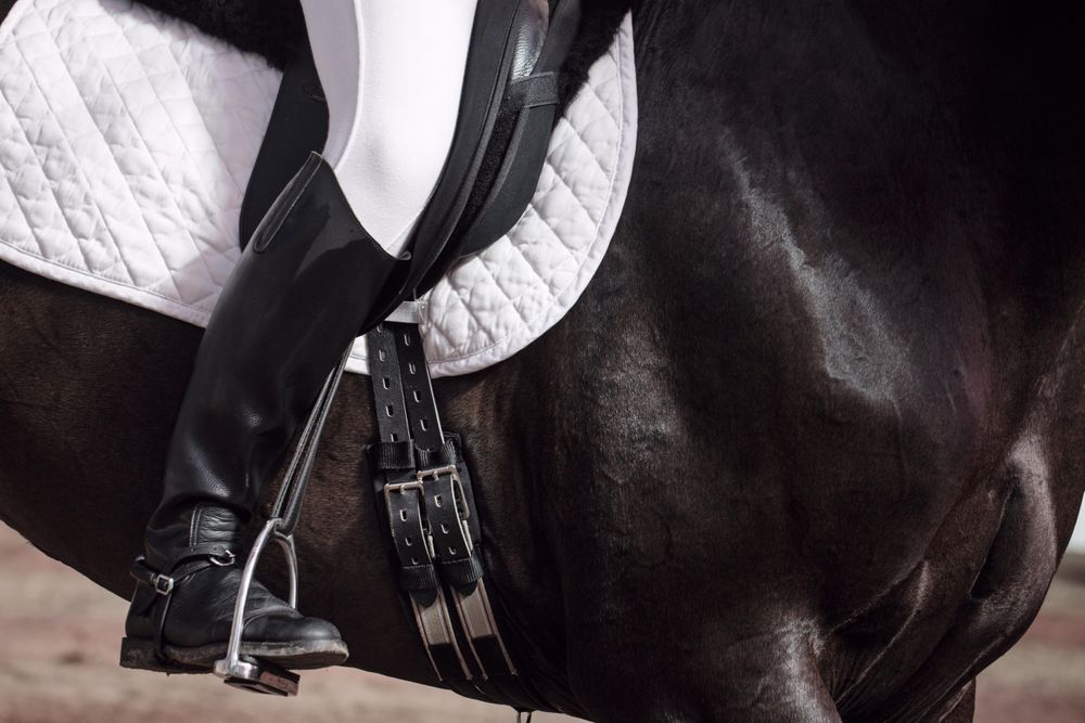 Boots of horseback rider in uniform on saddle on horse