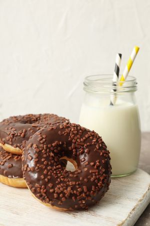 Jar of milk and tasty donuts on gray table