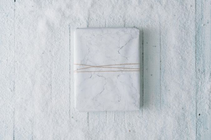 Wooden table background with snow and  wrapped present