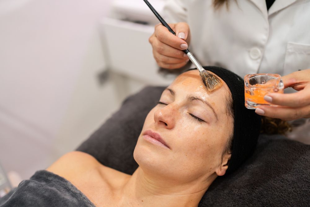 Cosmetologist brushing product on client's forehead