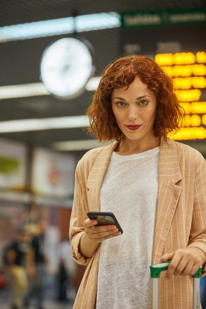 Red haired young woman using smartphone at station