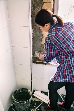 Bricklayer leveling cement with a trowel to tile the wall