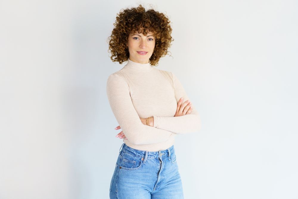 Confident woman with crossed arms against plain studio background