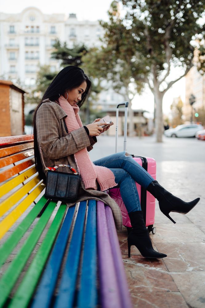 Asian traveler using smartphone on bench