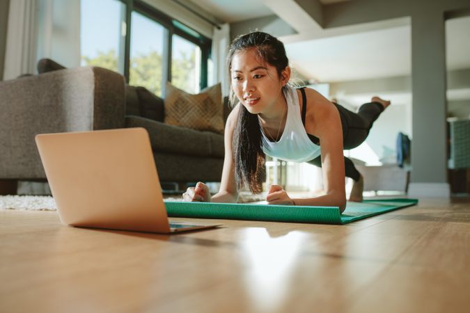 Woman working out at home watching video tutorial on laptop