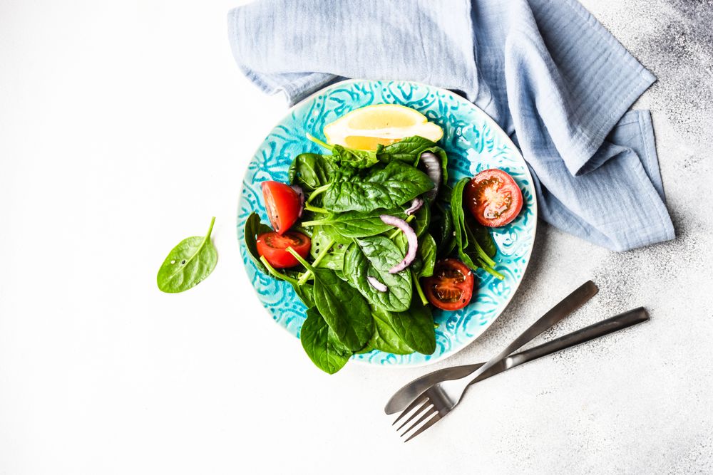 Top view of leafy spinach salad with lemon slice