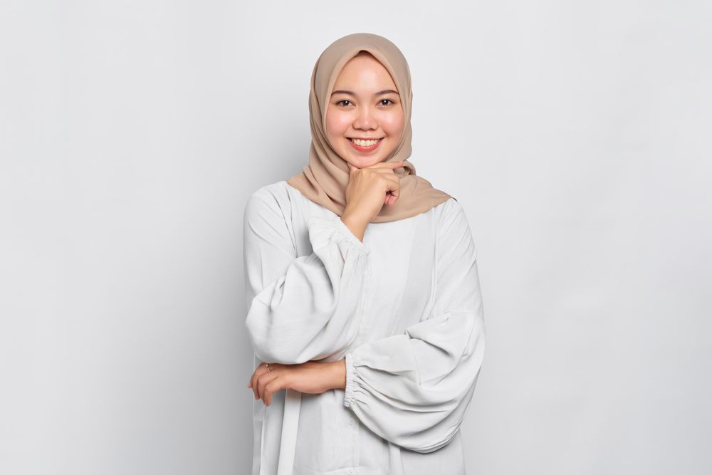 Smiling Asian female in headscarf with hand on chin