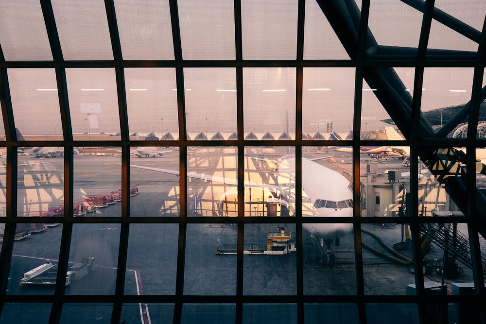 Airplane at gate viewed through large window with panes at airport