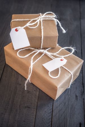Two presents wrapped in natural paper with twine on wood table