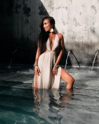 Smiling woman standing in dress in fountain pool