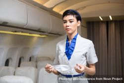 Flight attendant getting ready to put on facemask in airplane 5ql2p0