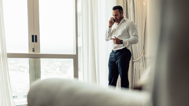 Businessman making a phone call on mobile from hotel room