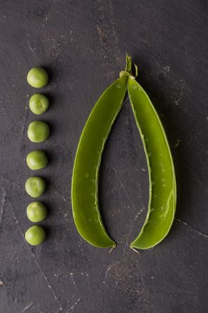 Fresh peas and pea pods on dark background