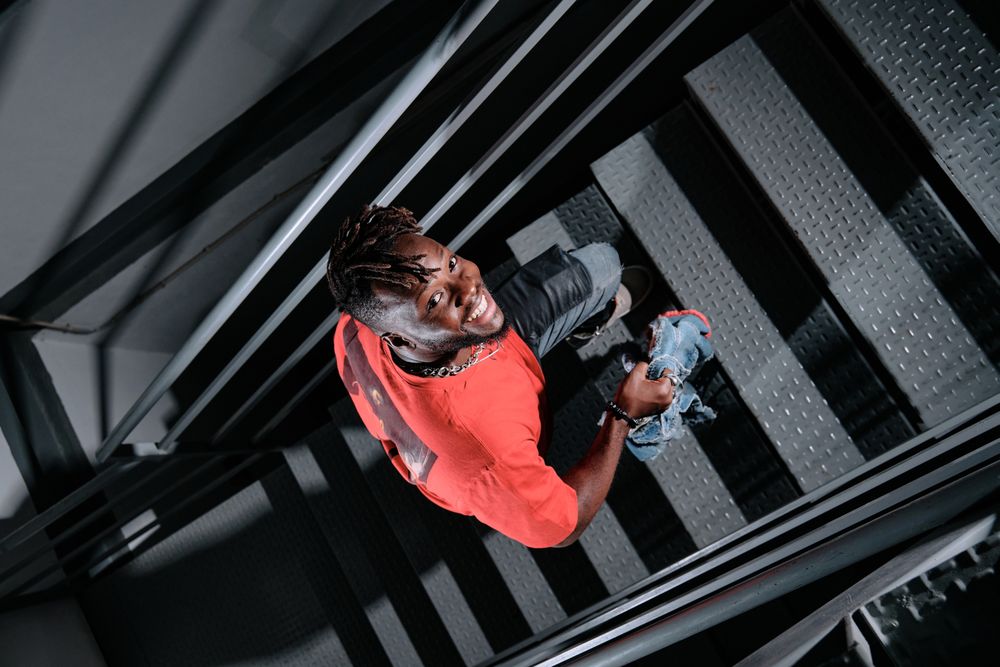 Happy Black man with dreadlocks going upstairs