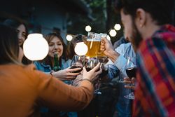 A lively group of friends toasting in the terrace of the restaurant pub in the countryside under the lights outdoors