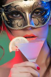 Woman in mask holding glass of drink