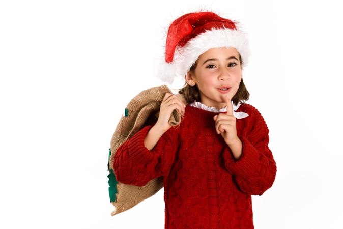 Child dressed as santa holding bag of presents