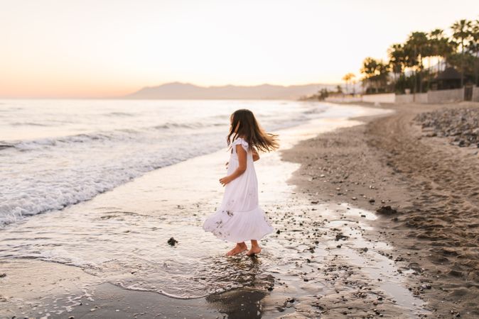 Excited girl running along beach in daylight