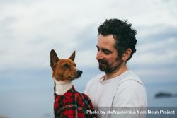 Sleepy dog wearing plaid shirt on a cliff with male owner 0gP8A5
