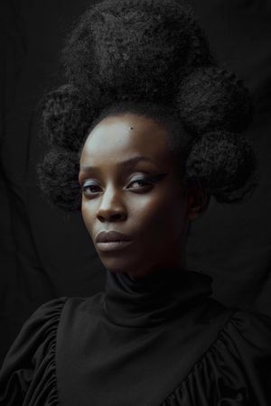 Portrait of Black woman in dark turtleneck shirt against dark background