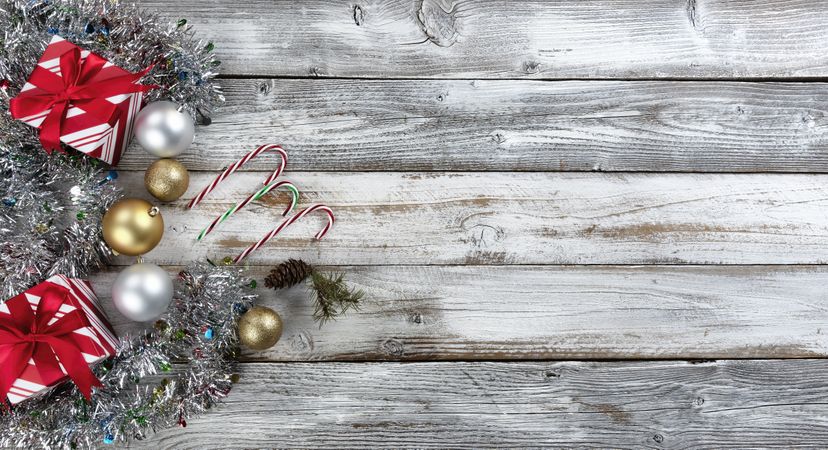 Traditional gold and silver balls with gifts surrounded by tinsel on a wood background