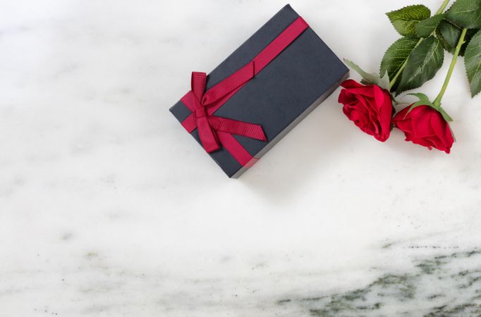 Red roses and packaged gift box on marble stone