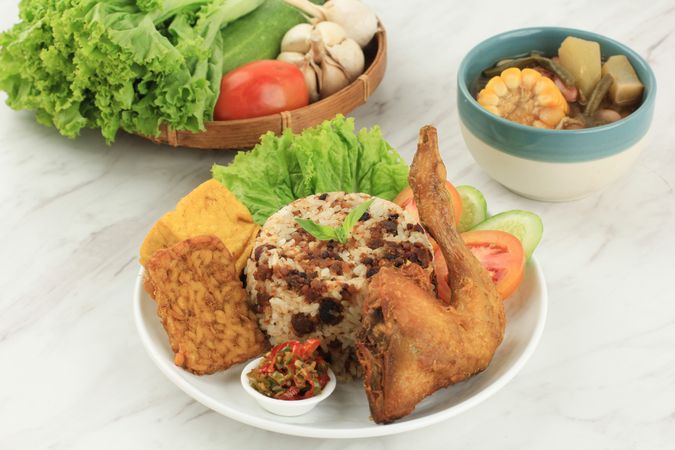 Indonesian chicken dish served with rice, salad and spicy condiment with cup of soup