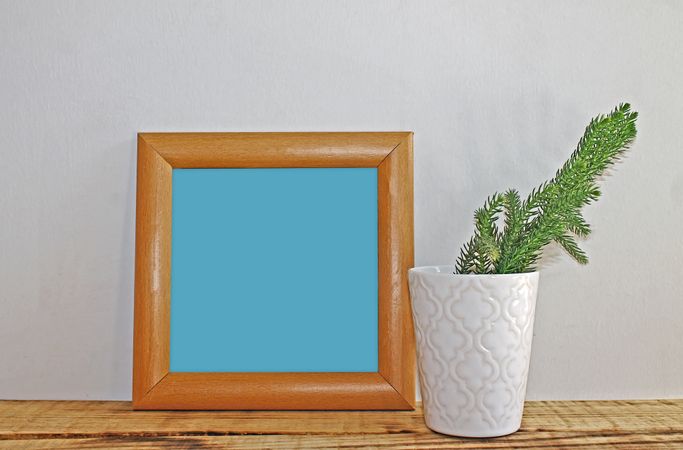 Plain square wooden picture frame with blue interior leaning against wall mockup