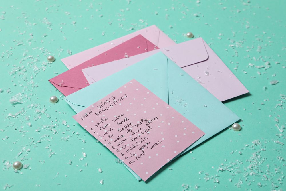 Envelopes and paper with list on green background