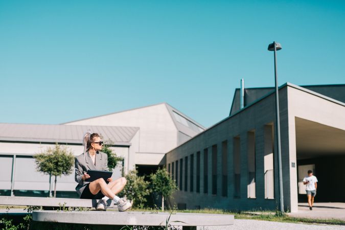 Stylish woman sitting and browsing tablet outside