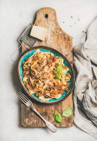 Pasta dinner with minced meat, and cheese on wooden board, vertical composition