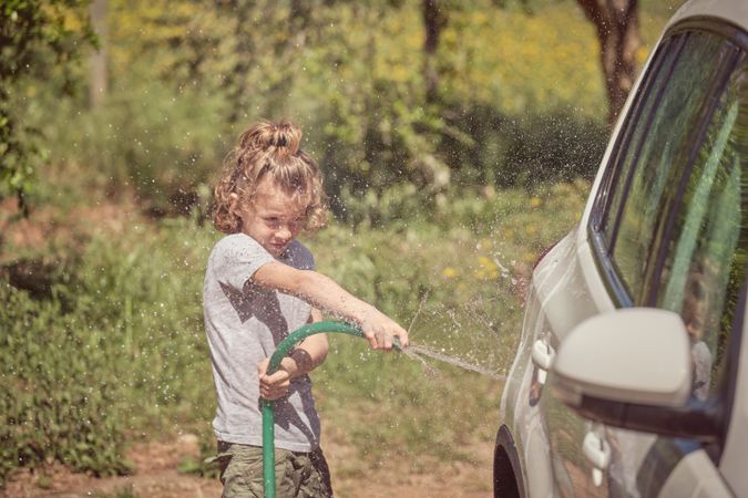 Little boy washing car in countryside