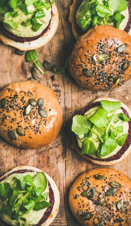 Fresh vegan burgers on seeded buns arranged on wooden board