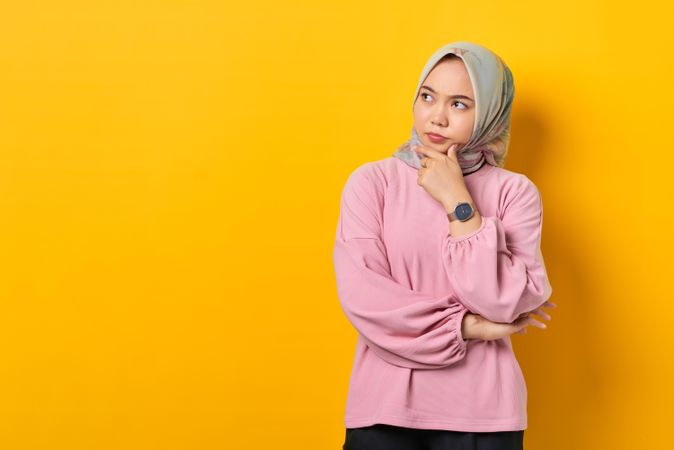 Muslim woman in headscarf in deep thought with hand on chin