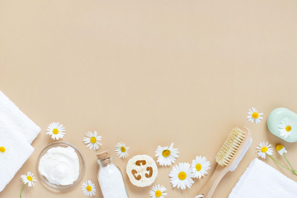 Relaxing bath salts, loofah and brushes on beige background with copy space
