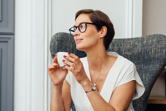 Woman thinking deeply sitting near stairs with a coffee