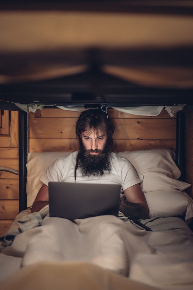 Man using laptop in rustic bunk bed