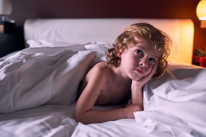Thoughtful boy lying on bed